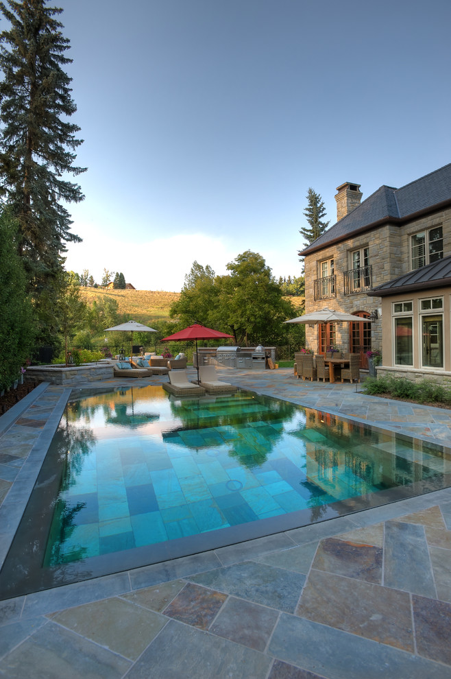 Inspiration for a mid-sized mediterranean backyard rectangular pool in Calgary with natural stone pavers.