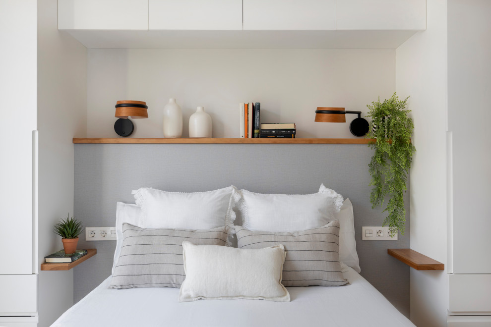 Modelo de dormitorio principal y gris y blanco actual de tamaño medio con paredes blancas y suelo de madera en tonos medios