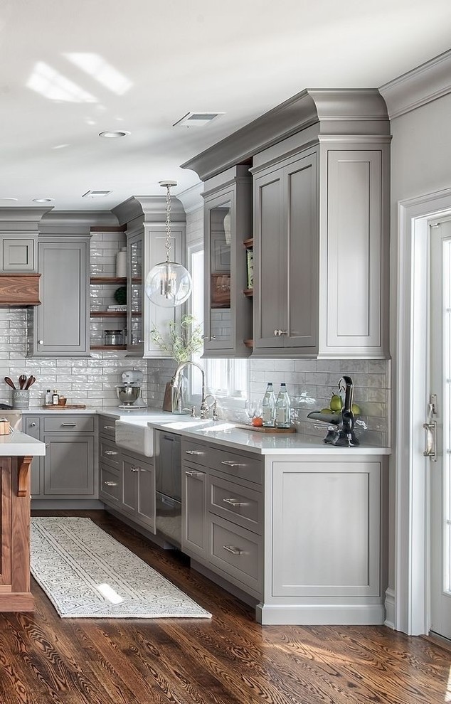 Design ideas for a transitional l-shaped kitchen in Seattle with a farmhouse sink, recessed-panel cabinets, grey cabinets, white splashback, stainless steel appliances, medium hardwood floors, with island, brown floor and white benchtop.