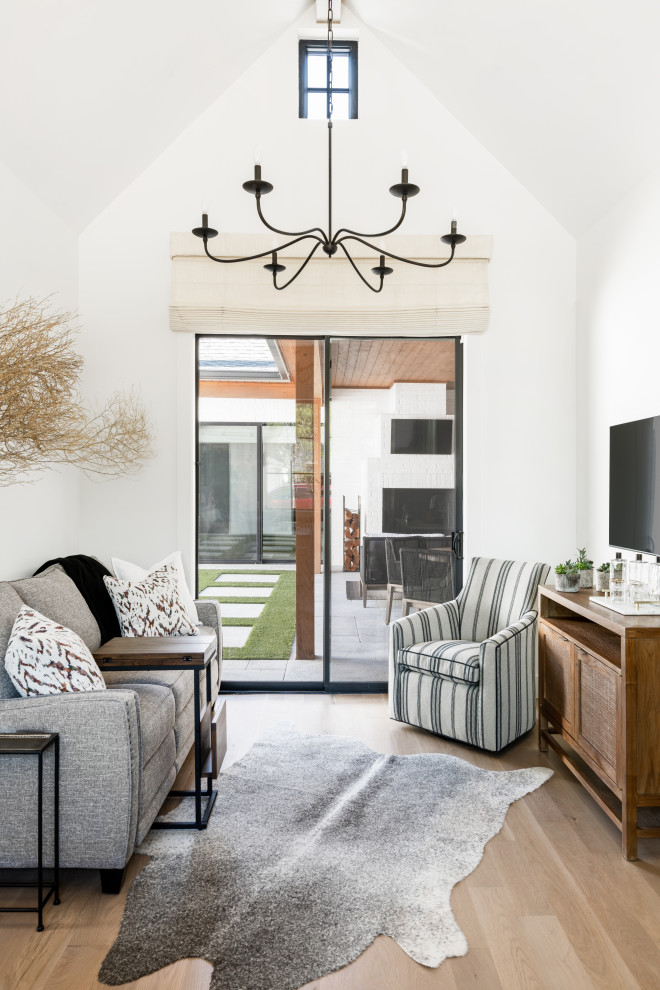 Mid-sized transitional open concept living room in Dallas with white walls, medium hardwood floors, a wall-mounted tv, brown floor and vaulted.