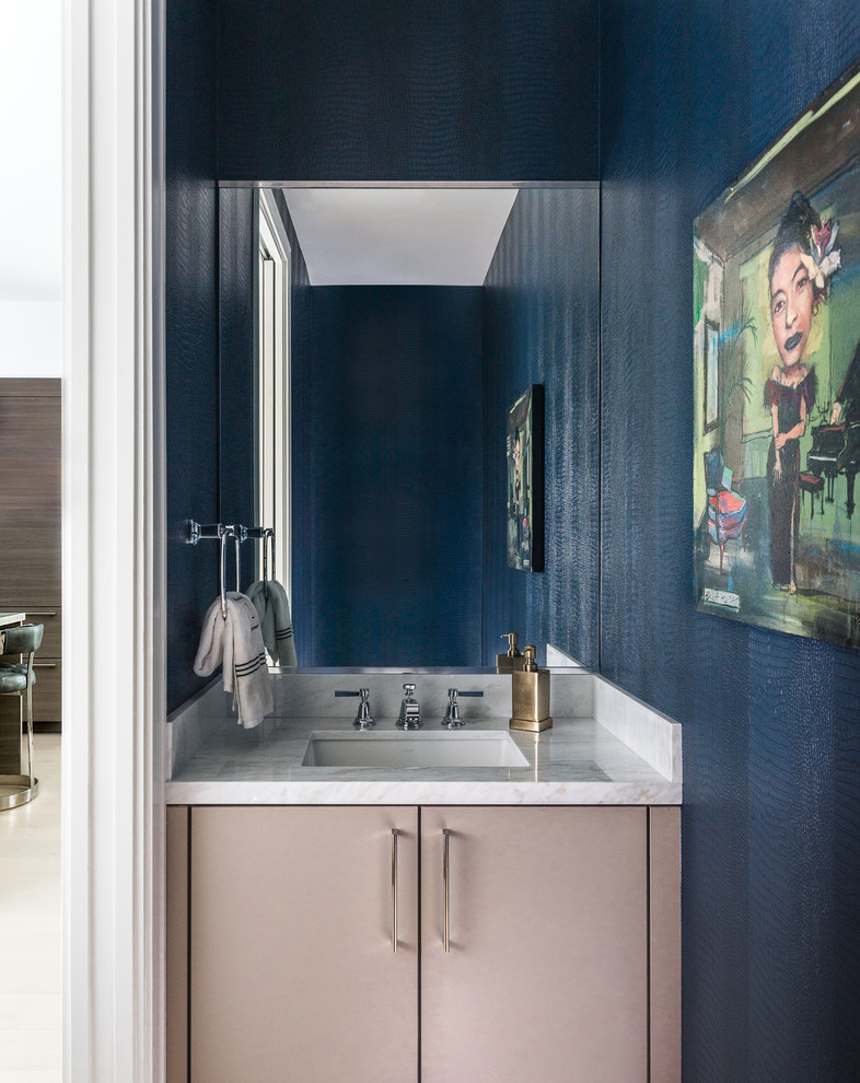 This is an example of a small contemporary powder room in Houston with flat-panel cabinets, beige cabinets, blue walls, an undermount sink and white benchtops.