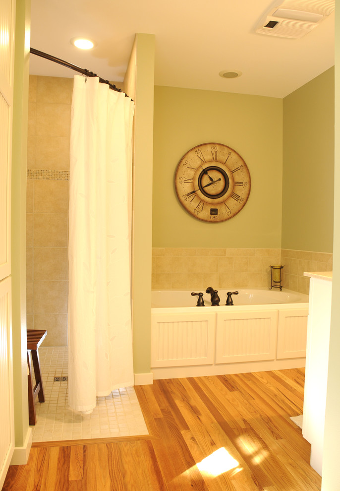 Photo of a bathroom in Other with a drop-in tub, a corner shower, white tile, green walls and light hardwood floors.