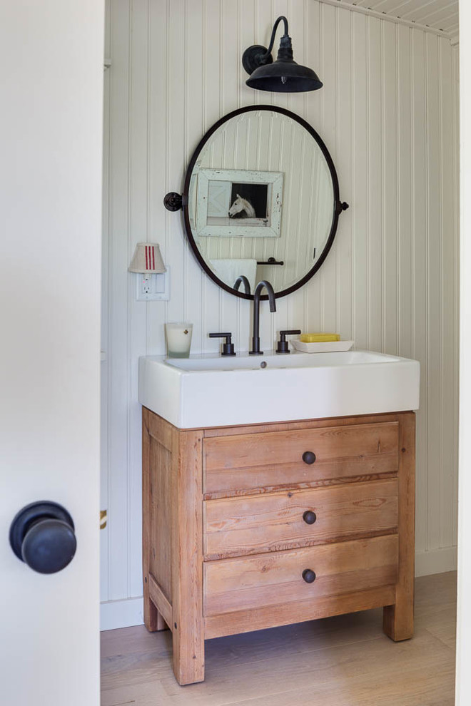 Inspiration for a mid-sized beach style 3/4 bathroom in Boston with raised-panel cabinets, light wood cabinets, a one-piece toilet, white walls, light hardwood floors and a trough sink.