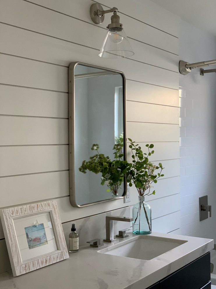 This is an example of a small farmhouse family bathroom in San Francisco with shaker cabinets, blue cabinets, an alcove bath, an alcove shower, a one-piece toilet, white tiles, ceramic tiles, white walls, marble flooring, a submerged sink, engineered stone worktops, black floors, a shower curtain, white worktops, a wall niche, double sinks, a built in vanity unit and tongue and groove walls.