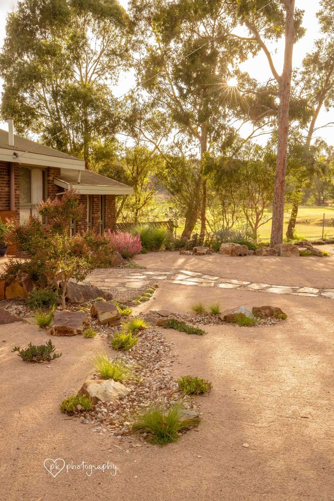 This is an example of a mid-sized and australian native contemporary front yard partial sun garden in Melbourne with natural stone pavers.