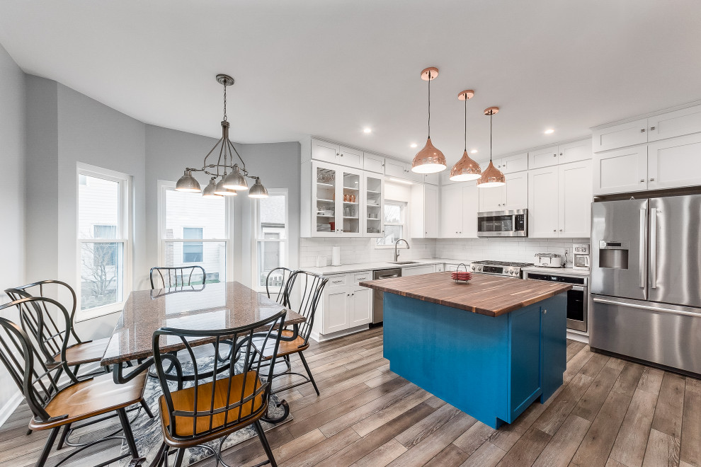 Inspiration for a mid-sized transitional l-shaped eat-in kitchen remodel in Columbus with shaker cabinets, quartz countertops, white backsplash, subway tile backsplash and an island