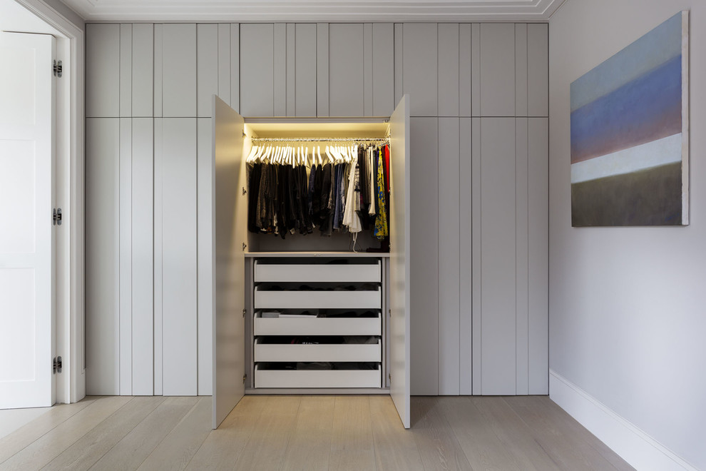 Photo of a contemporary gender neutral standard wardrobe in London with medium hardwood flooring.