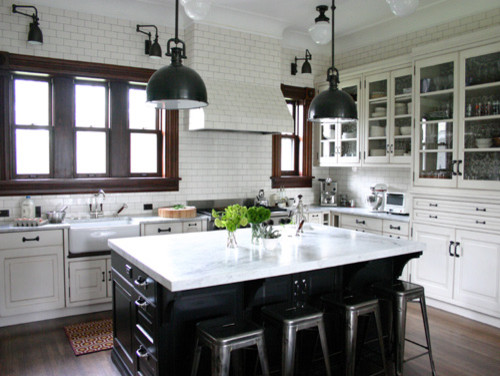 This is an example of a large traditional u-shaped kitchen in Chicago with a farmhouse sink, raised-panel cabinets, white cabinets, marble benchtops, white splashback, subway tile splashback, stainless steel appliances, medium hardwood floors, with island, brown floor and white benchtop.