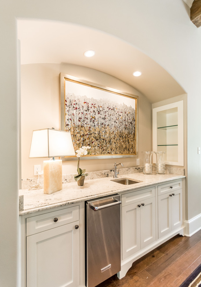 Photo of a large transitional single-wall wet bar in New Orleans with an undermount sink, shaker cabinets, white cabinets, granite benchtops and dark hardwood floors.