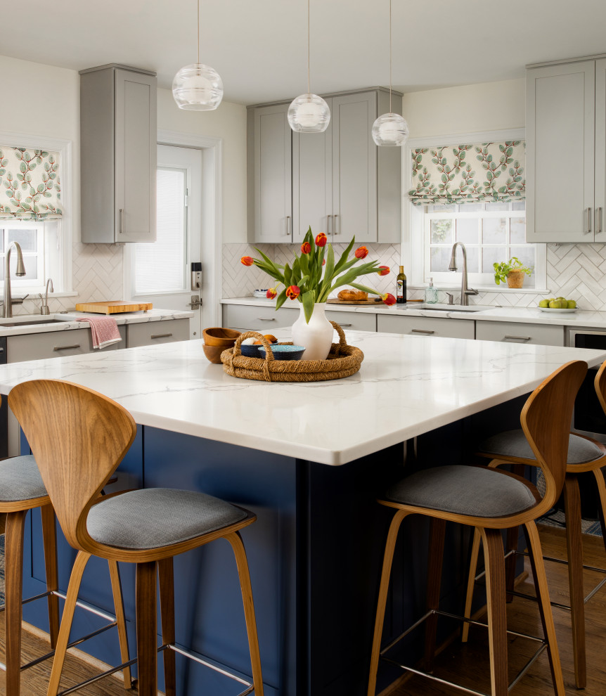 Transitional l-shaped separate kitchen in DC Metro with an undermount sink, shaker cabinets, blue cabinets, quartz benchtops, white splashback, porcelain splashback, stainless steel appliances, medium hardwood floors, with island, brown floor and white benchtop.