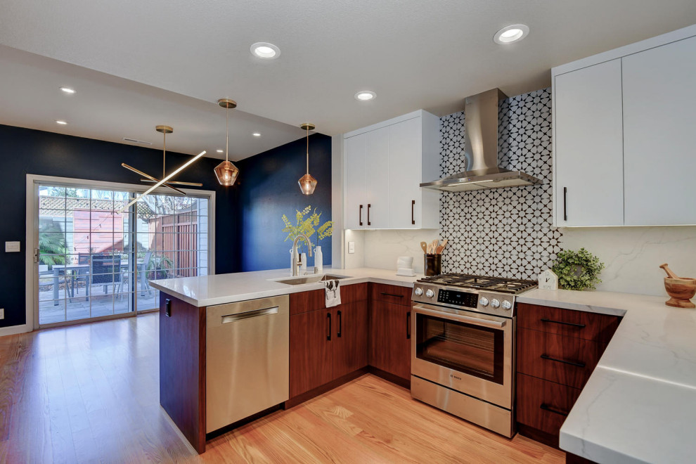 Small modern u-shaped eat-in kitchen in San Francisco with a single-bowl sink, flat-panel cabinets, distressed cabinets, quartzite benchtops, multi-coloured splashback, ceramic splashback, stainless steel appliances, medium hardwood floors, a peninsula, brown floor and white benchtop.