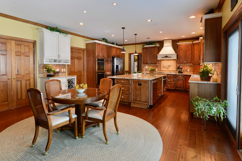 Large transitional u-shaped medium tone wood floor eat-in kitchen photo with beaded inset cabinets, medium tone wood cabinets, granite countertops, beige backsplash, mosaic tile backsplash, stainless steel appliances and an island