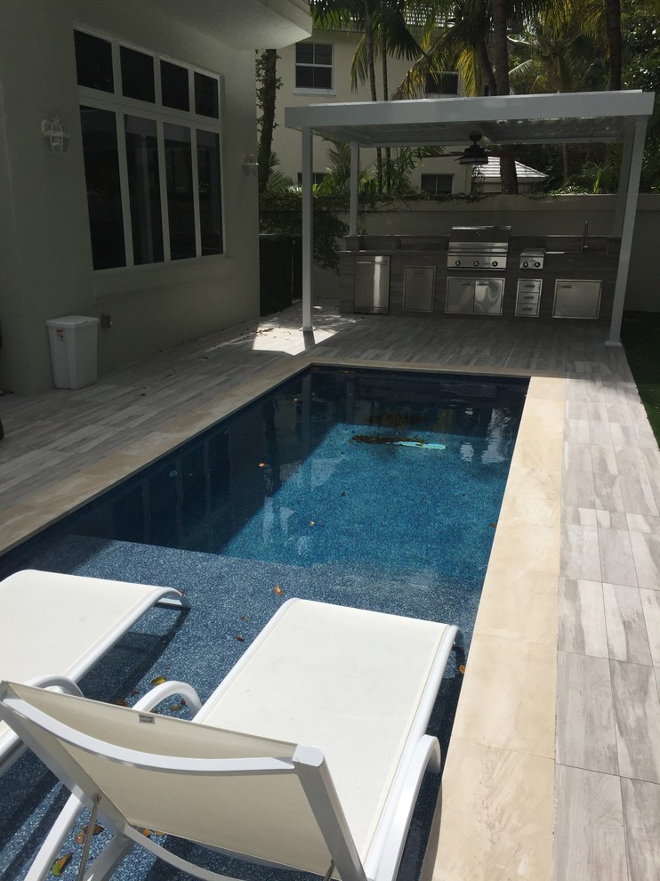 Photo of a small contemporary backyard rectangular lap pool in Miami with tile.