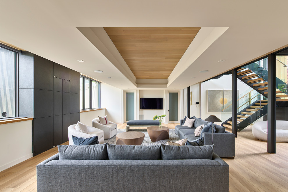 Example of a large minimalist light wood floor and coffered ceiling basement design in Philadelphia with a home theater and white walls