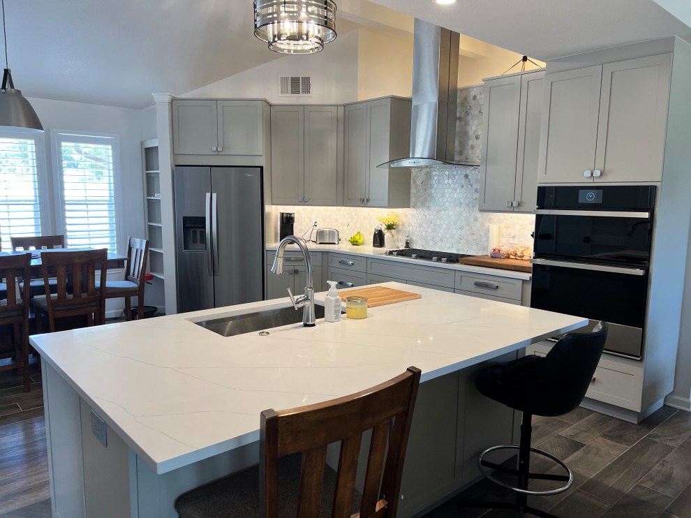 Eat-in kitchen - large transitional u-shaped porcelain tile and brown floor eat-in kitchen idea in Austin with an undermount sink, shaker cabinets, gray cabinets, quartz countertops, white backsplash, marble backsplash, stainless steel appliances, an island and white countertops