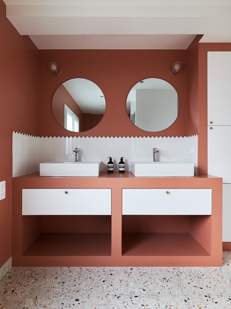 Photo of a large contemporary ensuite bathroom in Paris with red cabinets, a submerged bath, white tiles, ceramic tiles, red walls, terrazzo flooring, a built-in sink, multi-coloured floors, red worktops, double sinks, a freestanding vanity unit and flat-panel cabinets.