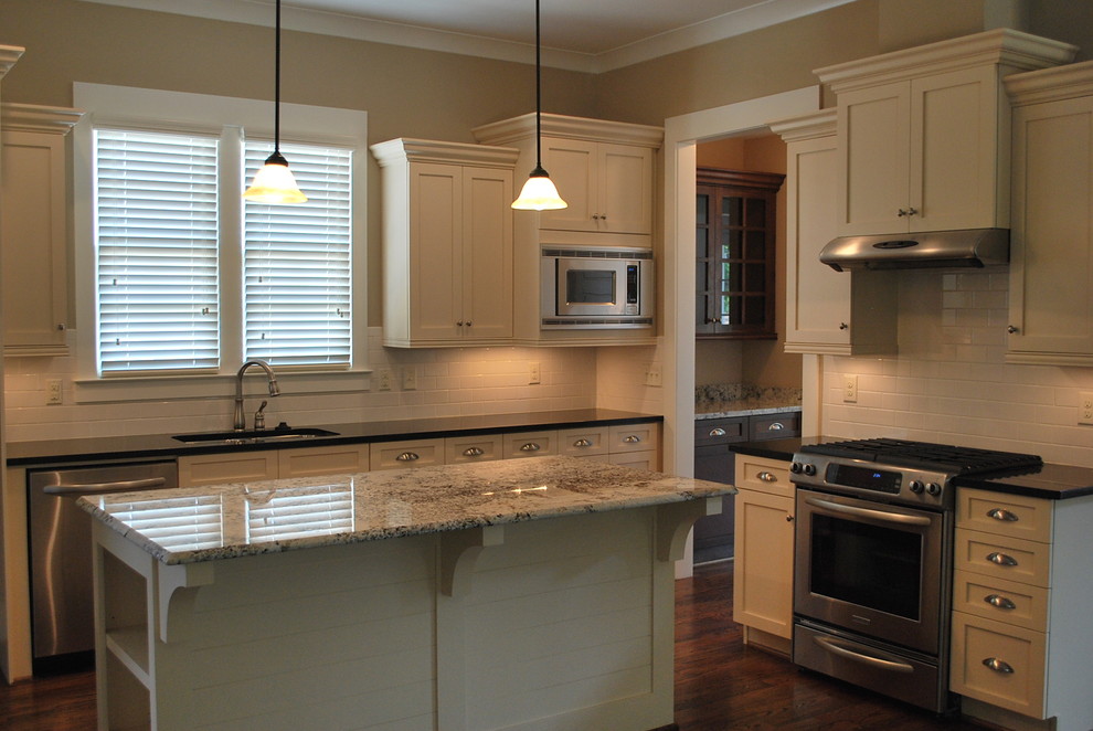 Inspiration for a small transitional l-shaped medium tone wood floor kitchen remodel in Birmingham with a drop-in sink, recessed-panel cabinets, white cabinets, granite countertops, white backsplash, subway tile backsplash, stainless steel appliances and an island
