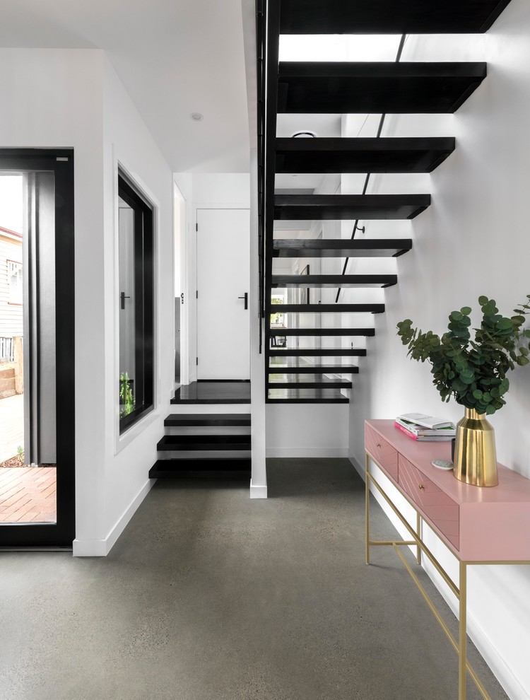 This is an example of a contemporary foyer in Brisbane with white walls, concrete floors, a single front door, a white front door and grey floor.