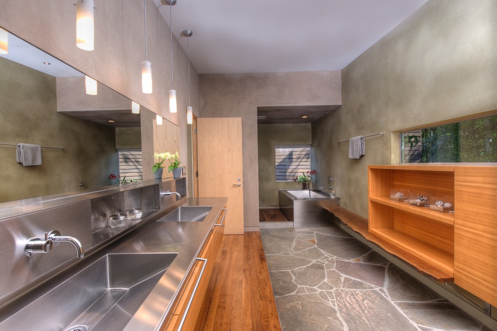 Modern bathroom in San Francisco with an integrated sink, open cabinets, medium wood cabinets, stainless steel benchtops, grey walls and an undermount tub.
