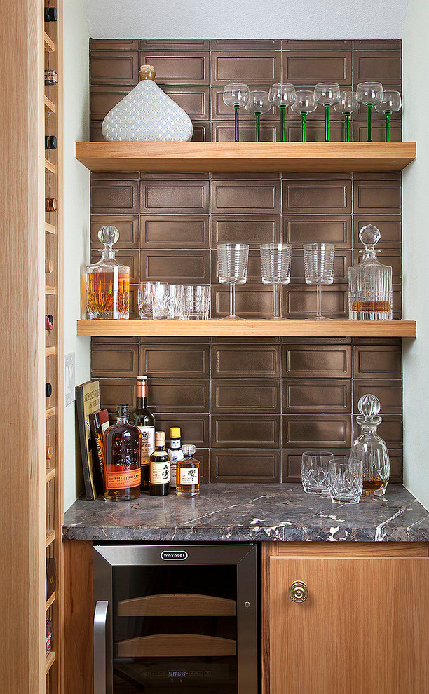 This is an example of a transitional single-wall home bar in Austin with no sink, light wood cabinets, metal splashback and flat-panel cabinets.