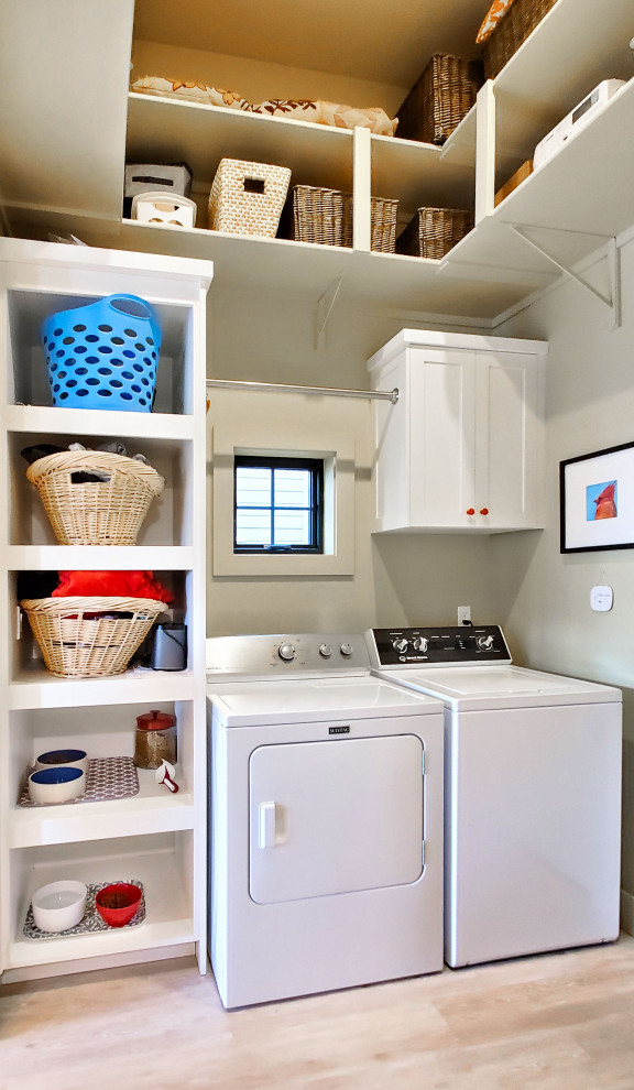 Photo of a small eclectic galley utility room in Boise with open cabinets, white cabinets, beige walls, vinyl floors, a side-by-side washer and dryer and beige floor.