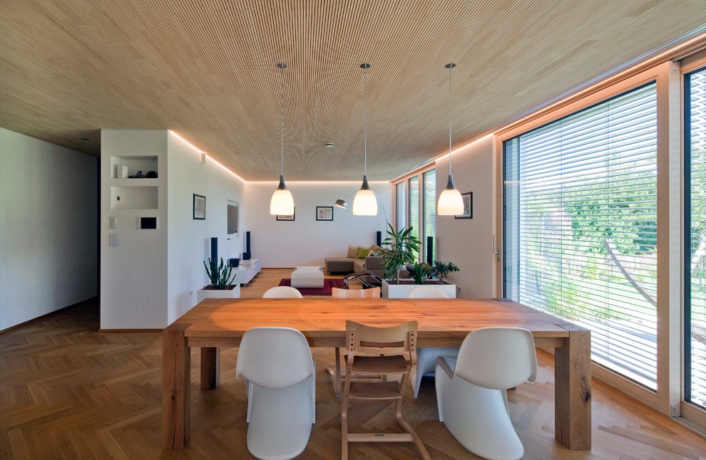 Photo of a large contemporary open plan dining in Munich with white walls, medium hardwood floors and brown floor.