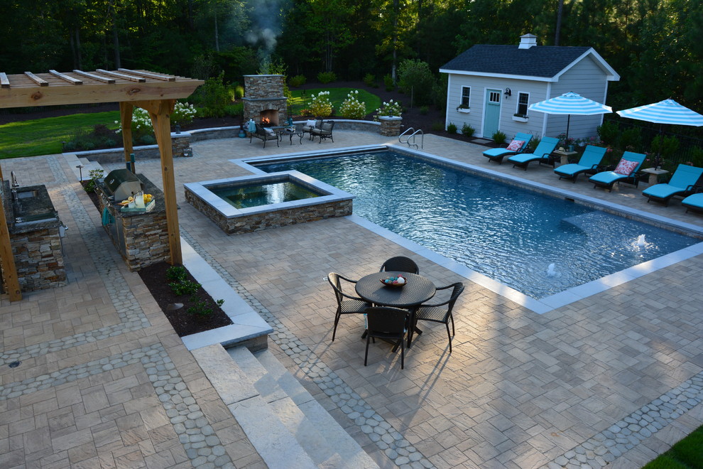 This is an example of a large traditional backyard rectangular lap pool in Richmond with a hot tub and concrete pavers.
