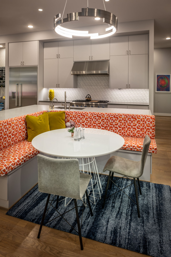 Mid-sized transitional l-shaped light wood floor and brown floor open concept kitchen photo in Houston with an undermount sink, flat-panel cabinets, gray cabinets, quartzite countertops, white backsplash, ceramic backsplash, stainless steel appliances, an island and white countertops