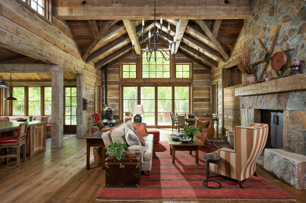 This is an example of a rustic formal open plan living room in Other with medium hardwood flooring, a standard fireplace, a stacked stone fireplace surround, no tv, a wood ceiling and wood walls.