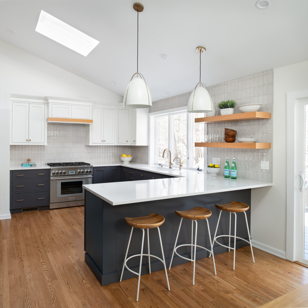 Design ideas for a mid-sized transitional u-shaped eat-in kitchen in New York with an undermount sink, beaded inset cabinets, grey cabinets, quartz benchtops, grey splashback, porcelain splashback, stainless steel appliances, medium hardwood floors and white benchtop.