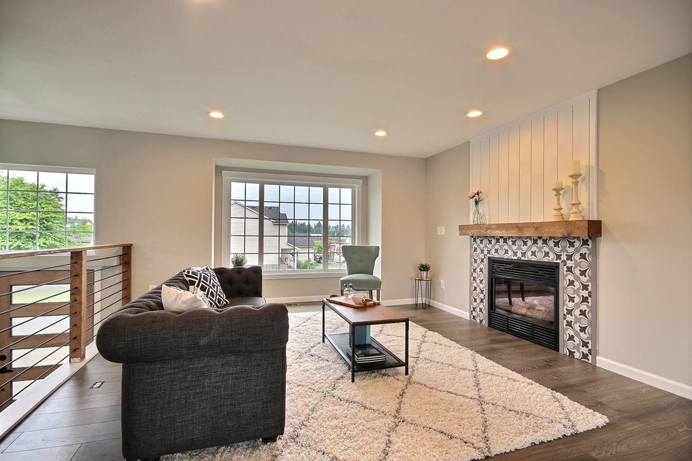 Photo of a mid-sized country open concept living room in Seattle with grey walls, laminate floors, a standard fireplace, a tile fireplace surround and grey floor.