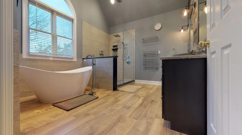 На фото: большая главная ванная комната в классическом стиле с фасадами с утопленной филенкой, темными деревянными фасадами, отдельно стоящей ванной, угловым душем, раздельным унитазом, бежевой плиткой, синими стенами, полом из ламината, настольной раковиной, коричневым полом, открытым душем, бежевой столешницей, тумбой под две раковины, встроенной тумбой, сводчатым потолком и деревянными стенами с