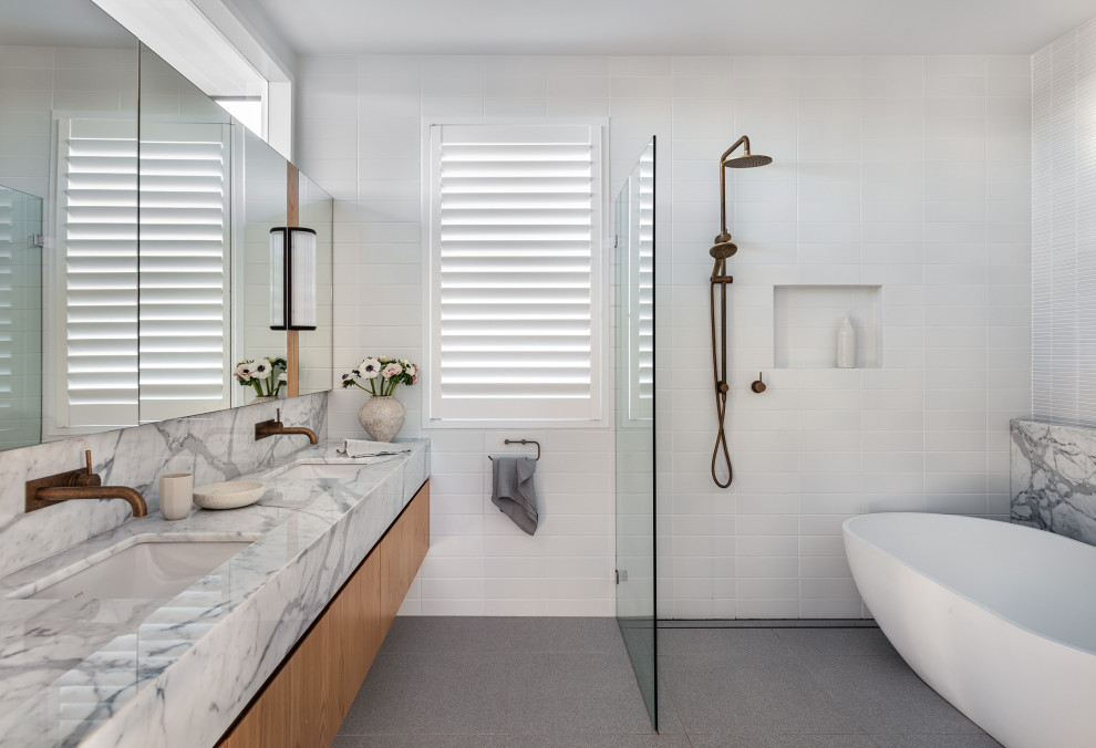 На фото: большая главная ванная комната в современном стиле с отдельно стоящей ванной, мраморной столешницей и встроенной тумбой