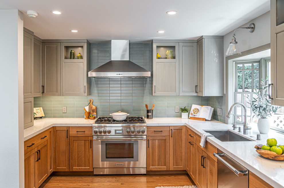 Design ideas for a transitional u-shaped kitchen in San Francisco with an undermount sink, shaker cabinets, medium wood cabinets, green splashback, stainless steel appliances, medium hardwood floors, no island, brown floor and white benchtop.