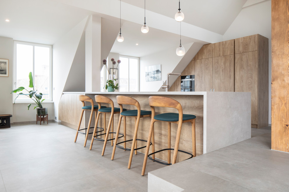 Expansive contemporary galley open plan kitchen in Berlin with a submerged sink, flat-panel cabinets, medium wood cabinets, tile countertops, ceramic flooring, an island, grey floors and grey worktops.