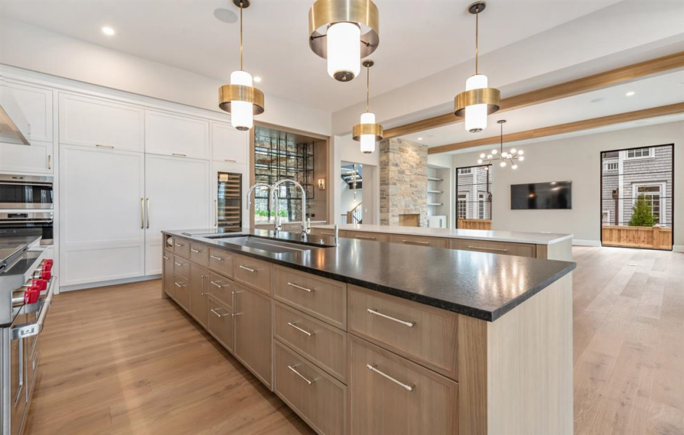 Kitchen - huge transitional single-wall light wood floor, brown floor and exposed beam kitchen idea in Chicago with an undermount sink, shaker cabinets, light wood cabinets, quartz countertops, white backsplash, quartz backsplash, paneled appliances, two islands and white countertops