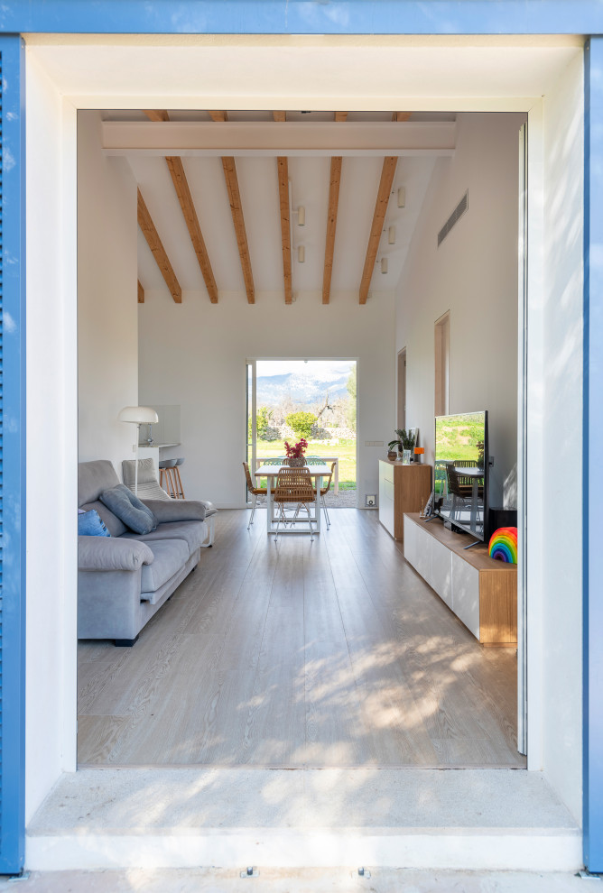 Kleines, Offenes Mediterranes Wohnzimmer ohne Kamin mit weißer Wandfarbe, Laminat, freistehendem TV, braunem Boden und freigelegten Dachbalken in Palma de Mallorca