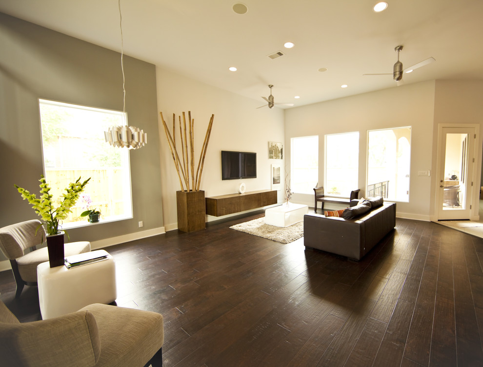 This is an example of a mid-sized contemporary formal open concept living room in Houston with white walls, dark hardwood floors, no fireplace, a freestanding tv and beige floor.