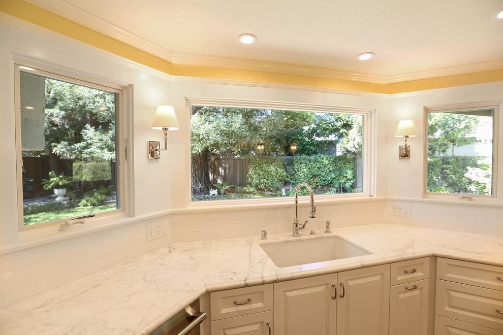 Mid-sized transitional u-shaped light wood floor enclosed kitchen photo in San Francisco with an undermount sink, beaded inset cabinets, white cabinets, marble countertops, white backsplash, subway tile backsplash, white appliances and an island