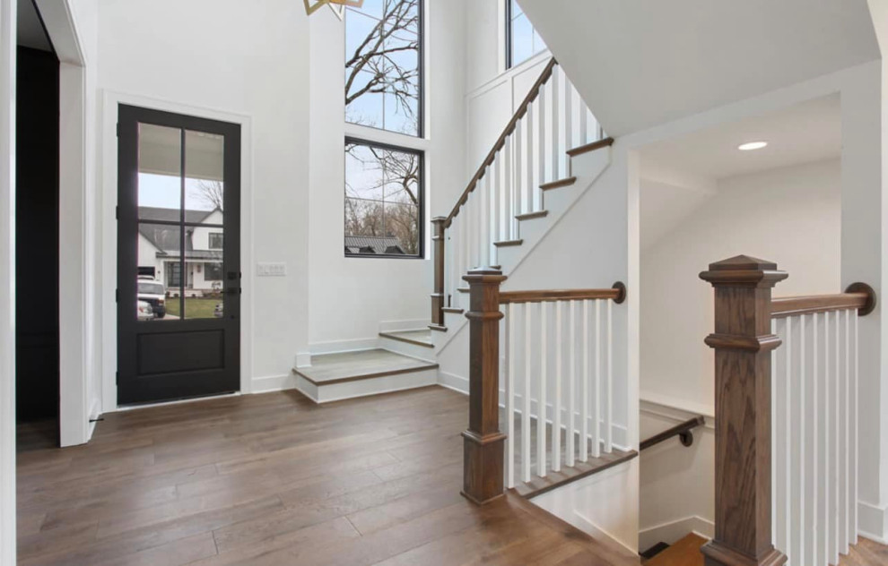 This is an example of a medium sized contemporary foyer in Cedar Rapids with white walls, light hardwood flooring, a single front door, a black front door, beige floors and a vaulted ceiling.