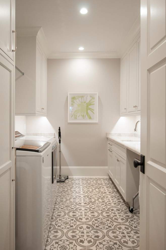 This is an example of a mid-sized traditional galley dedicated laundry room in Nashville with an undermount sink, beaded inset cabinets, white cabinets, quartzite benchtops, grey walls, concrete floors, a side-by-side washer and dryer, grey floor and white benchtop.