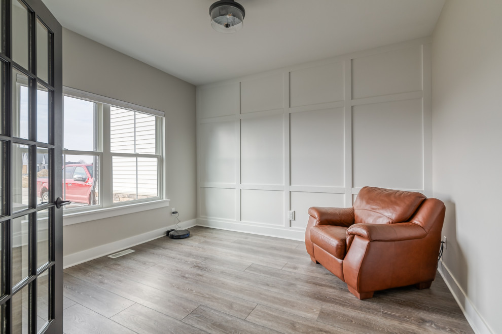 Immagine di una cameretta per neonati neutra minimalista di medie dimensioni con pareti beige, pavimento in vinile, pavimento marrone e pannellatura