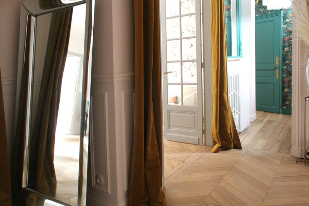 This is an example of a mid-sized transitional foyer in Paris with white walls and light hardwood floors.