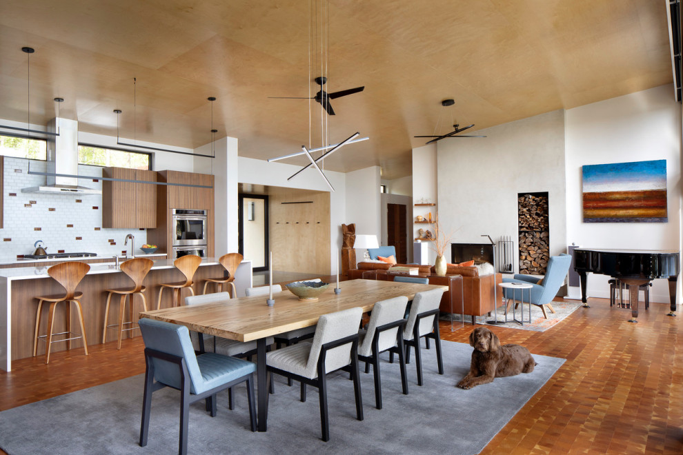 Foto di una sala da pranzo contemporanea con pareti bianche, pavimento in legno massello medio, camino classico, cornice del camino in cemento e soffitto in legno