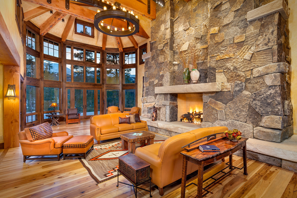 Country formal living room in Denver with light hardwood floors, a standard fireplace and a stone fireplace surround.