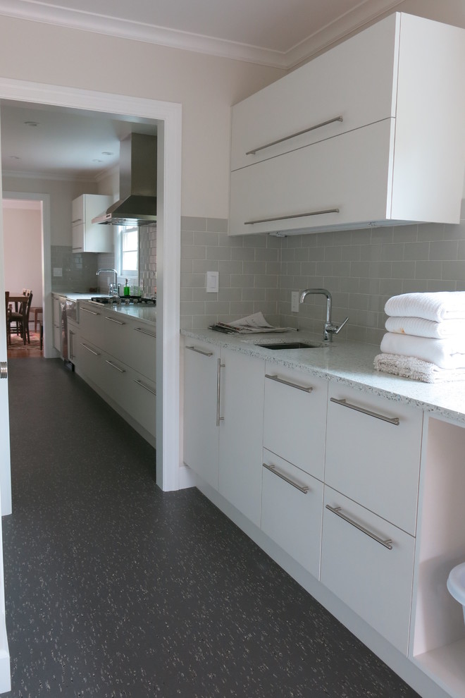 Photo of a modern laundry room in San Francisco with solid surface benchtops, an undermount sink and beige walls.