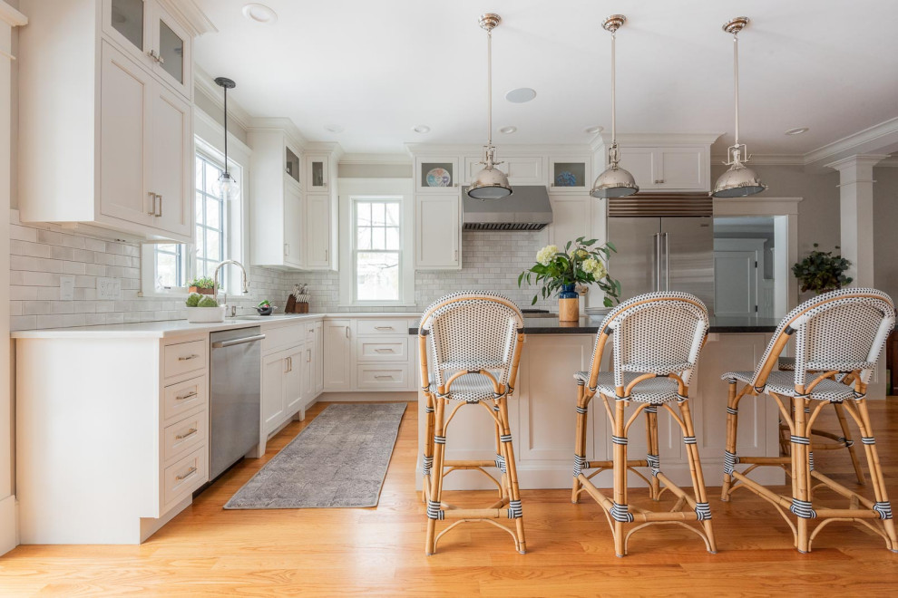 Eat-in kitchen - large transitional u-shaped medium tone wood floor and brown floor eat-in kitchen idea in Boston with an undermount sink, shaker cabinets, white cabinets, quartz countertops, gray backsplash, subway tile backsplash, stainless steel appliances, an island and black countertops