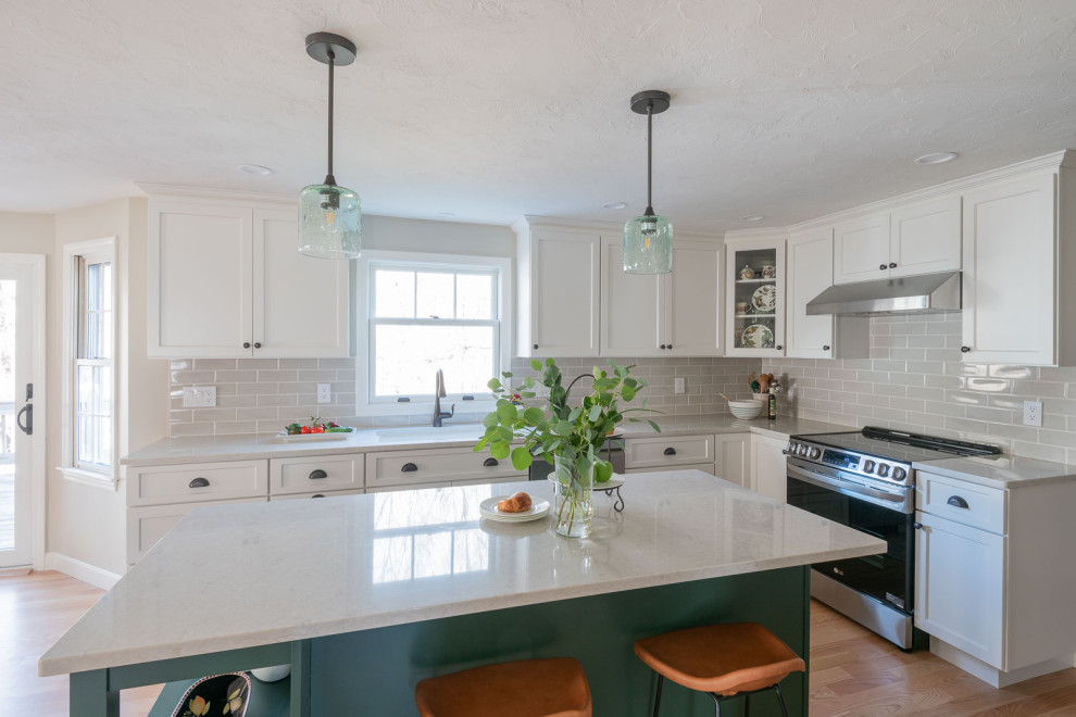 Example of a large transitional galley light wood floor and brown floor eat-in kitchen design in Boston with an undermount sink, shaker cabinets, white cabinets, quartz countertops, beige backsplash, ceramic backsplash, stainless steel appliances, an island and white countertops