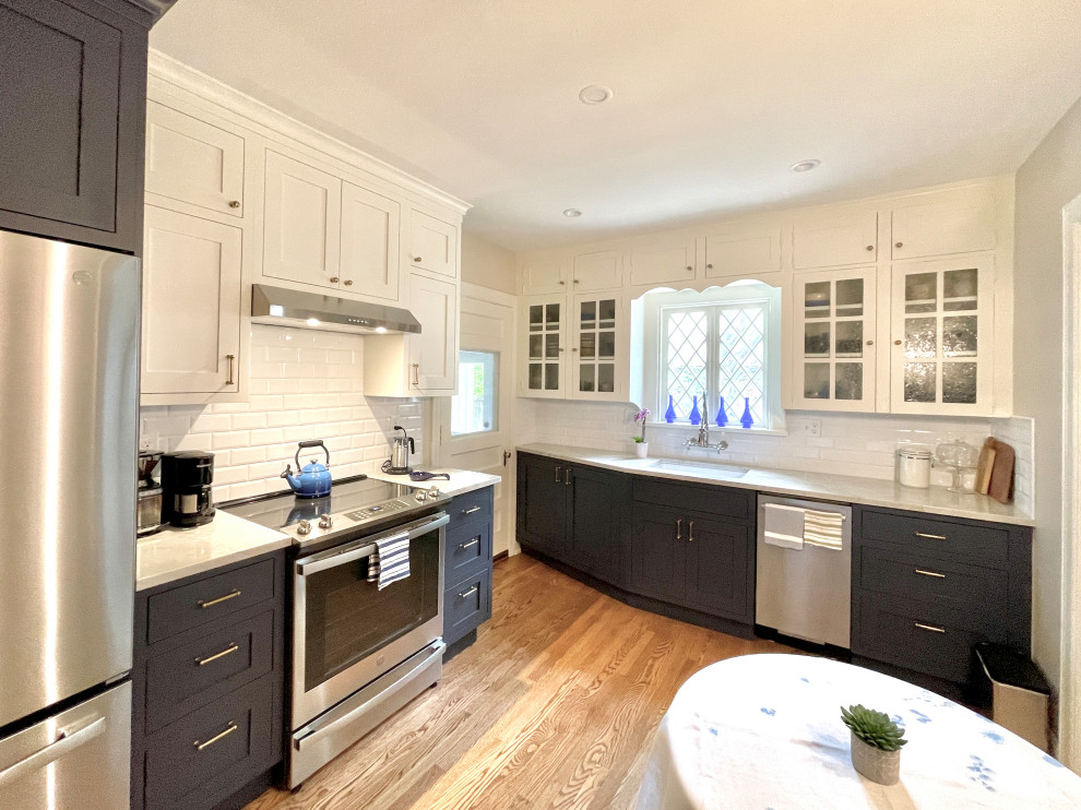 Photo of a small traditional u-shaped separate kitchen in Oklahoma City with a single-bowl sink, shaker cabinets, brown cabinets, quartz benchtops, white splashback, subway tile splashback, stainless steel appliances, medium hardwood floors, no island, brown floor and white benchtop.