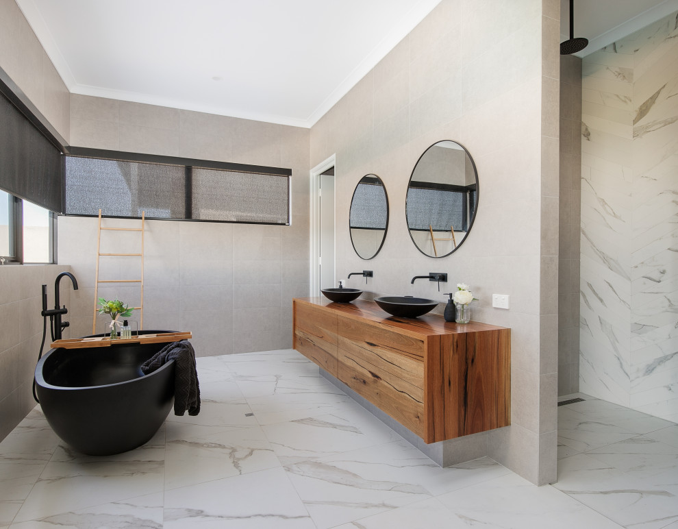 Inspiration for a large contemporary master bathroom in Perth with flat-panel cabinets, medium wood cabinets, a freestanding tub, gray tile, porcelain tile, a vessel sink, wood benchtops, grey floor, brown benchtops, a double vanity and a floating vanity.